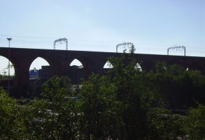 The buses turn below, while the 'Stockport Pyramid' is just visible through one of the arches